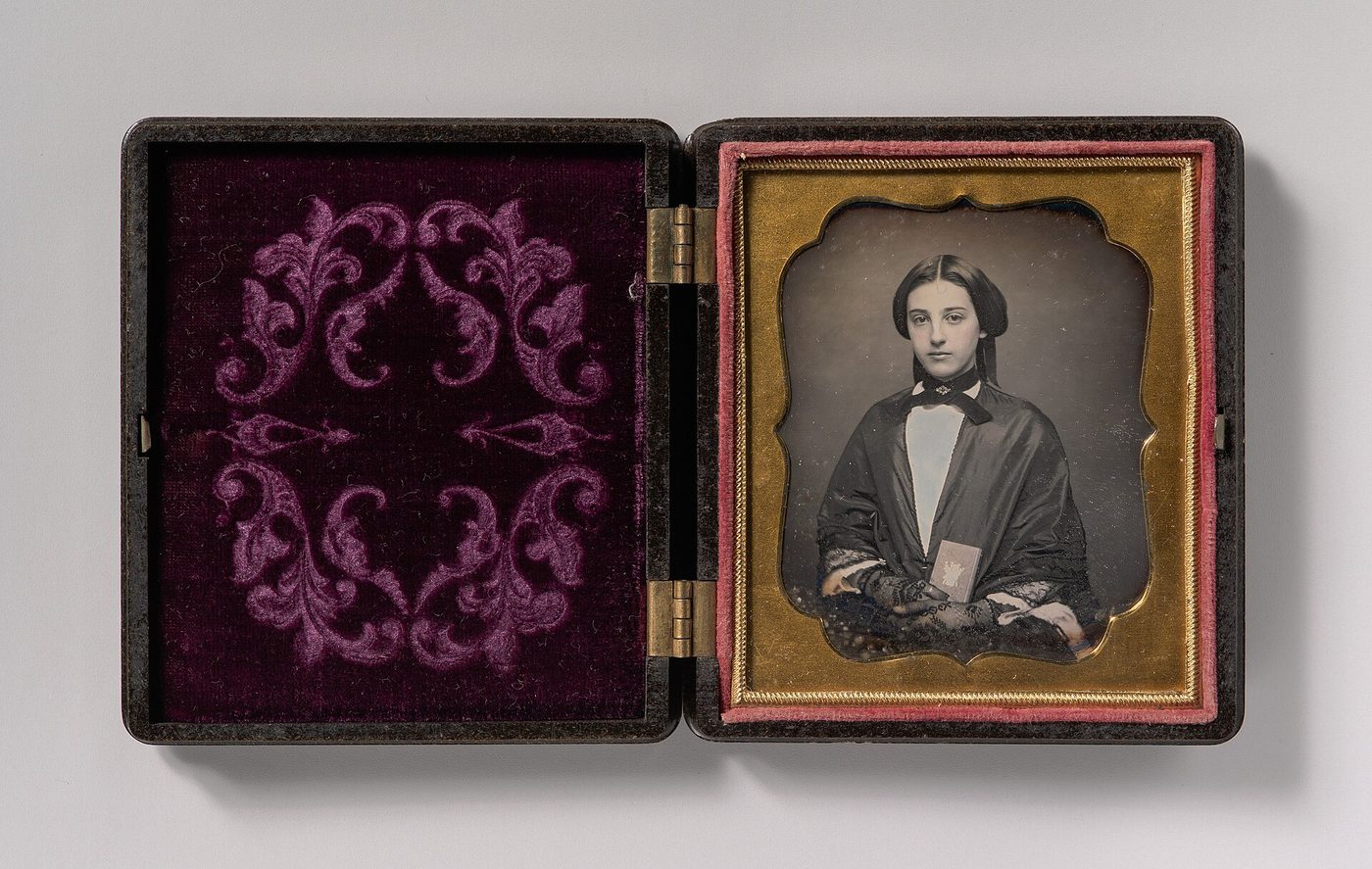 A nineteenth-century photograph of a young woman holding an open daguerreotype case